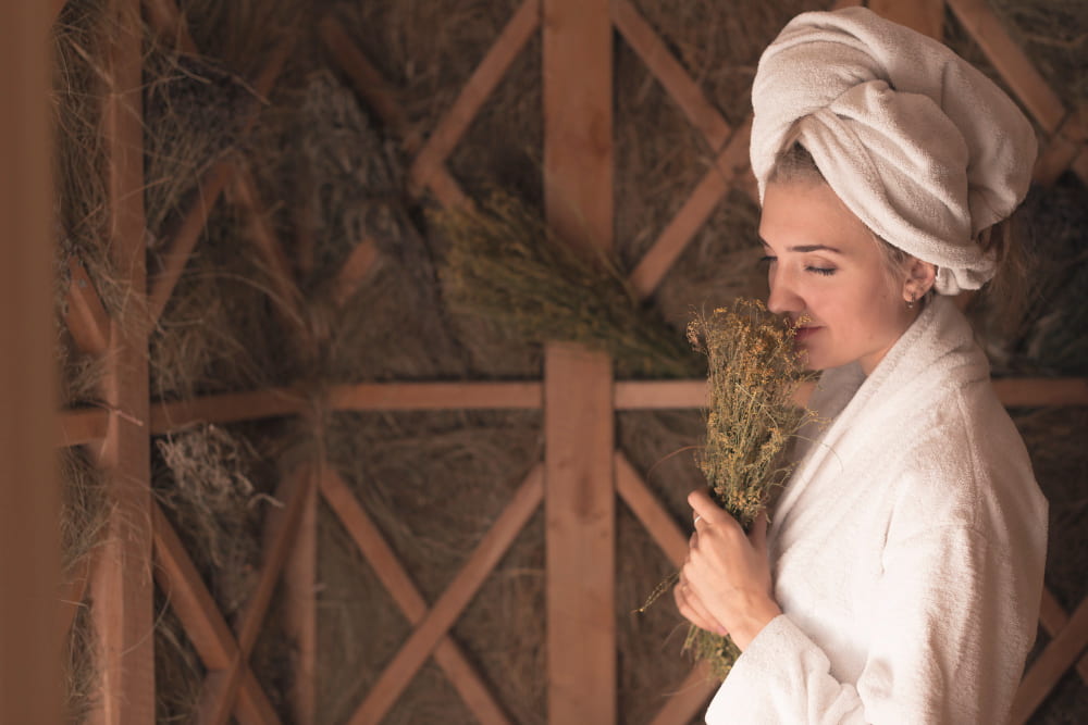 young-woman-smelling-herb-flowers-standing-in-the-sauna-min.jpg