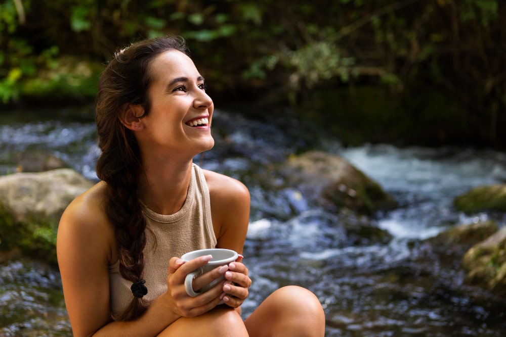 smiley-woman-relaxing-with-mug-in-nature-min.jpg