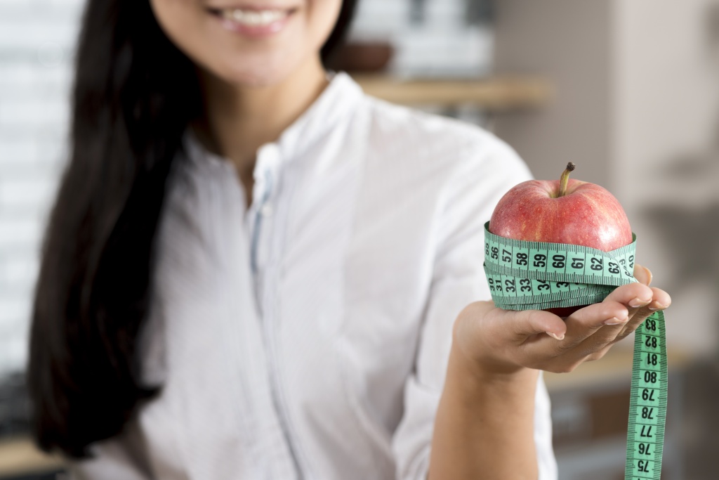 close-up-woman-s-hand-holding-red-apple-with-green-measurement-tape.jpg